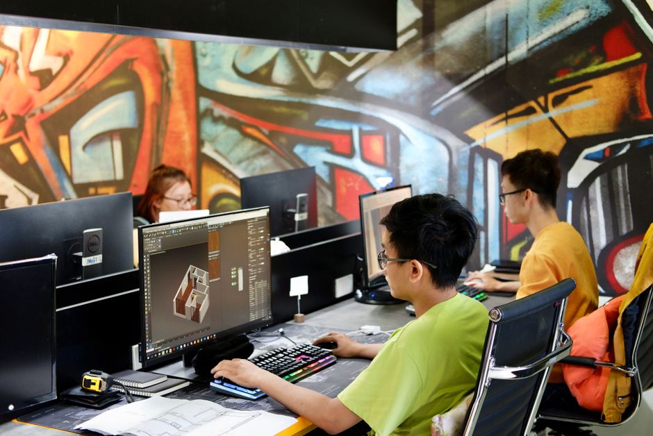 Three young people working on computers in a creative office with vibrant graffiti walls.